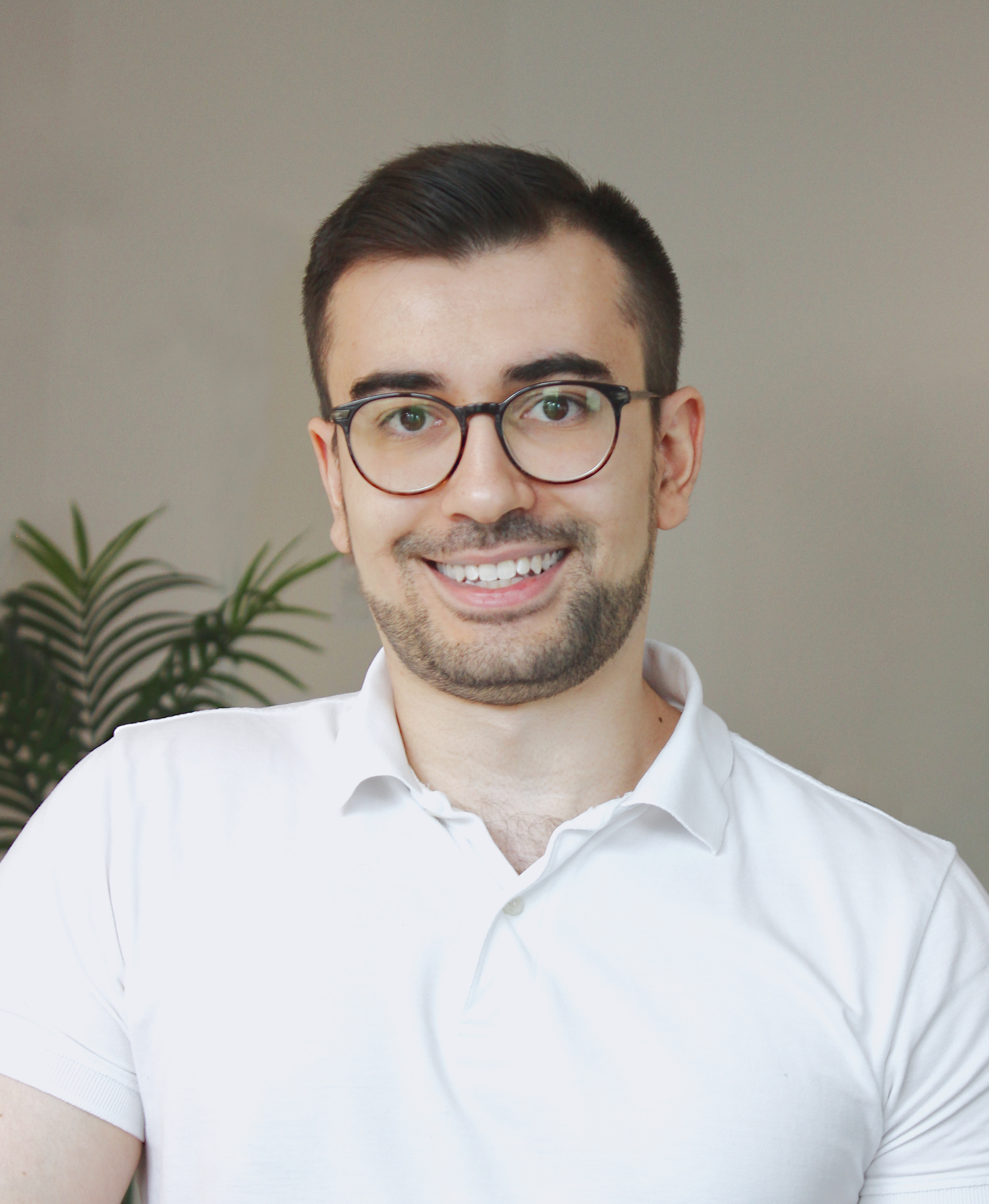 Zu sehen ist der Senior System Architekt. Ein Mann um die 30 Jahre alt, mit schwarzen Haaren, einer Brille und er trägt ein weißes Polo-Hemd.